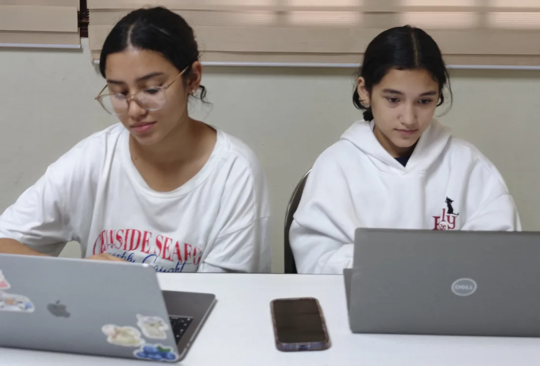 Dos estudiantes programan lado a lado en sus laptops en el Club de IA