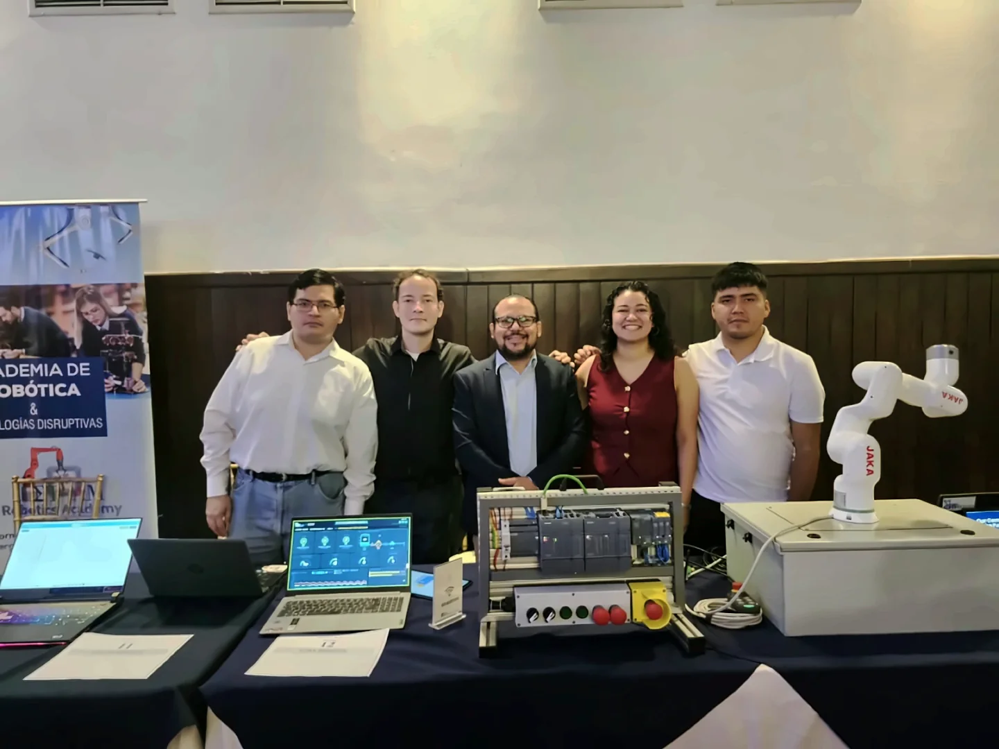Equipo de la academia en un stand de feria con un brazo robótico colaborativo