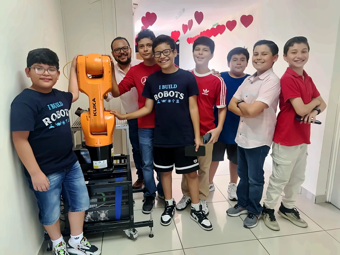 Estudiantes junto a un brazo robótico industrial