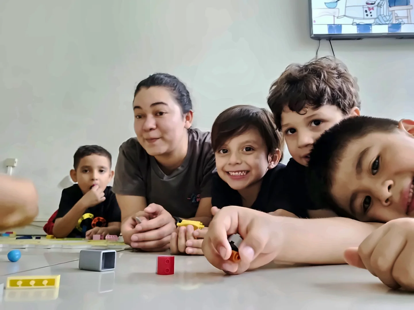 Niños de Robótica Inicial sonríen mientras construyen con bloques junto a su docente